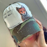 a woman wearing a camouflage hat with a fox on it